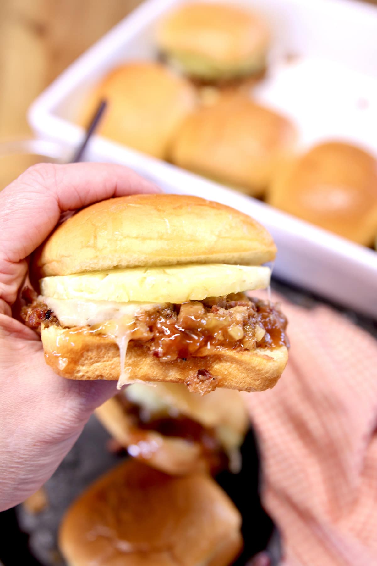 Closeup of pork slider with pineapple held in hand.