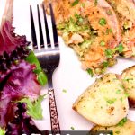 plate of sliced stuffed salmon with salad, fork and potatoes.