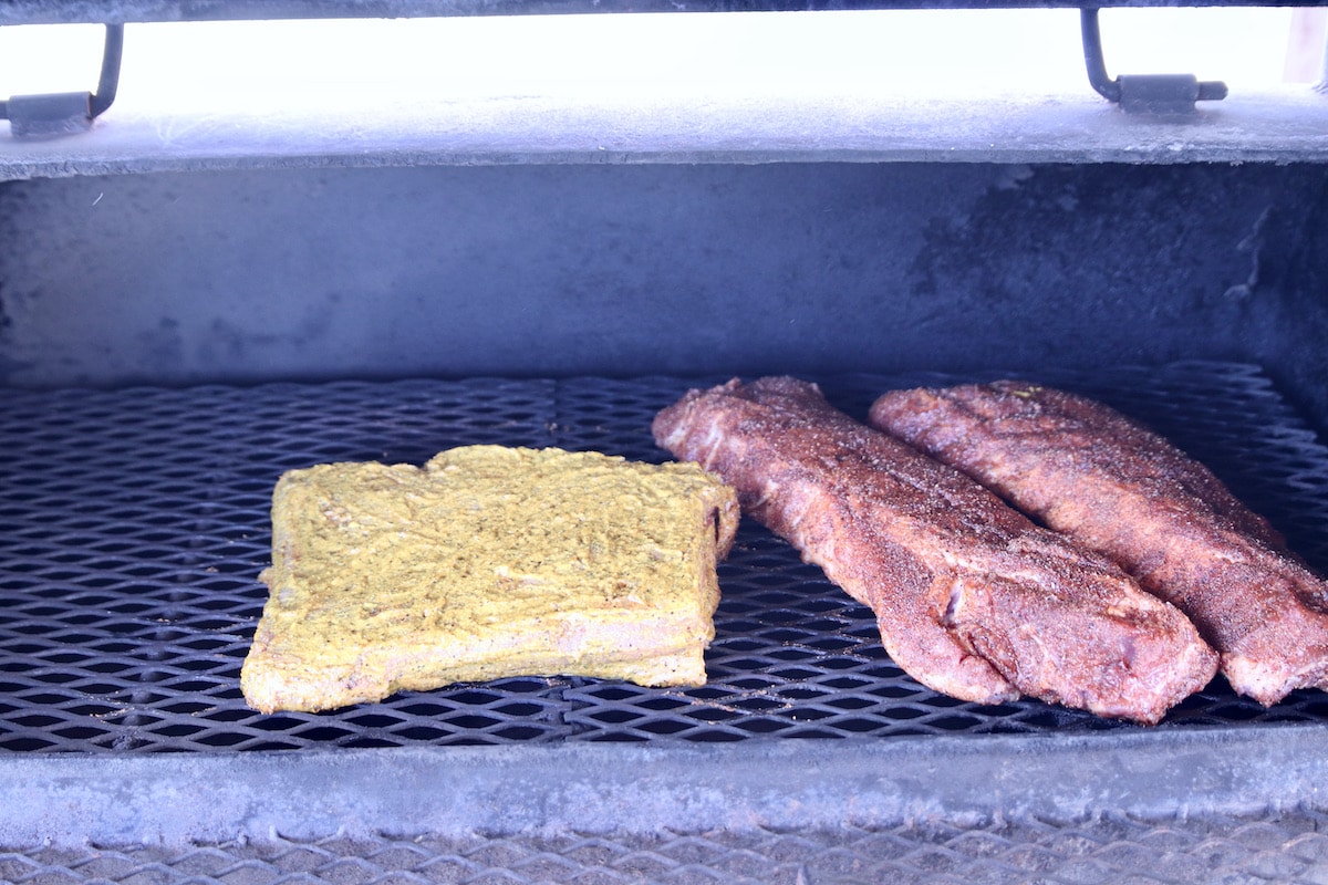 Brisket flat on a grill with 2 racks ribs.