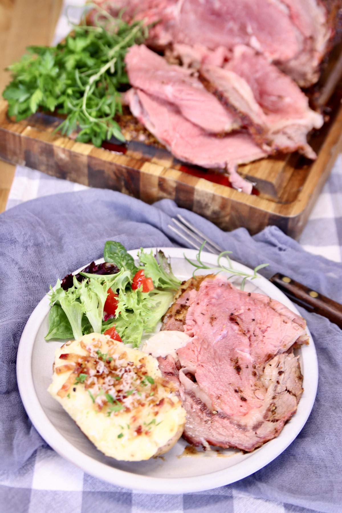 Overhead view of plate of prime rib, potato, salad.