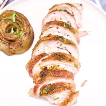 Bacon wrapped stuffed chicken, sliced on a plate.