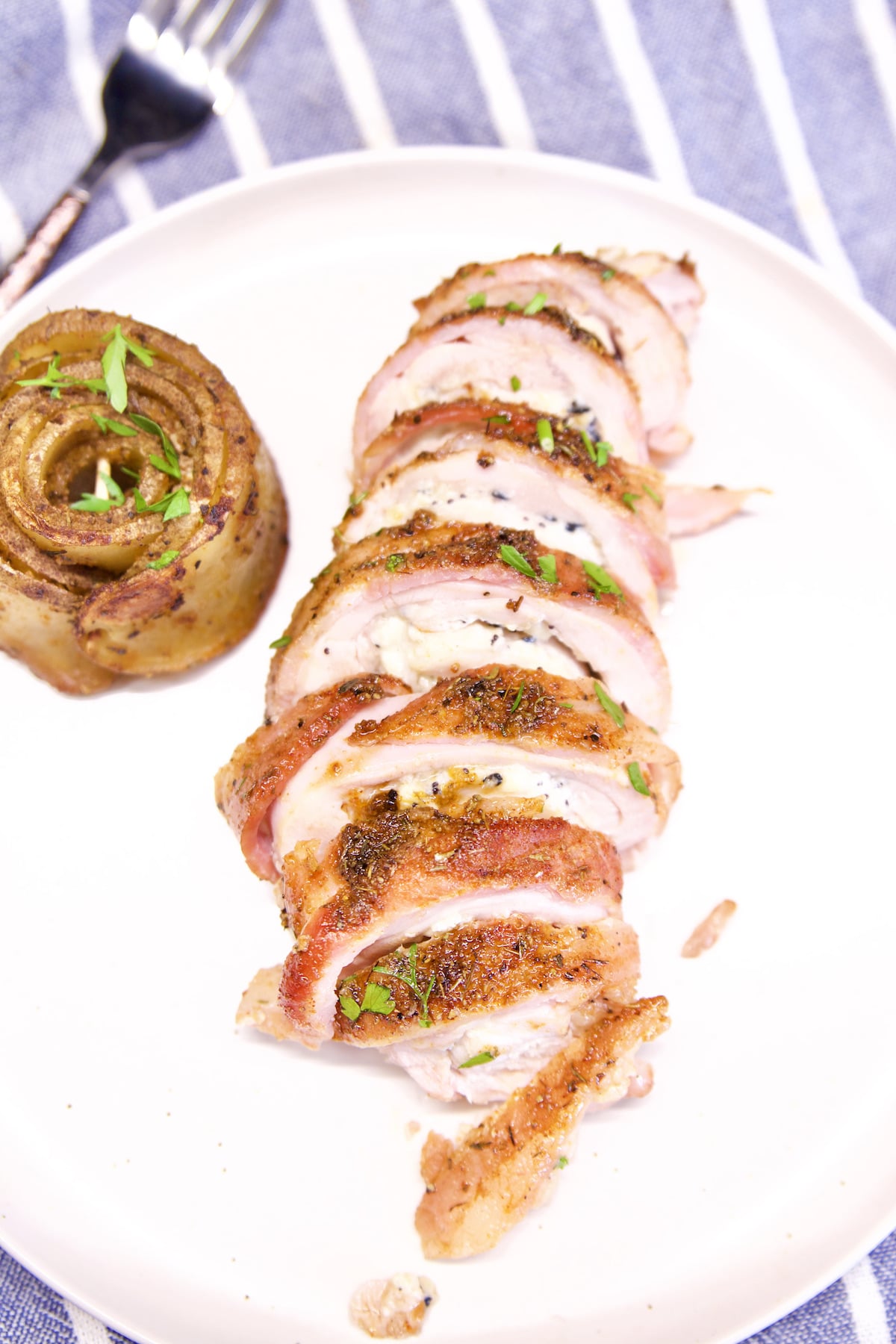 plate with sliced bacon wrapped stuffed chicken.