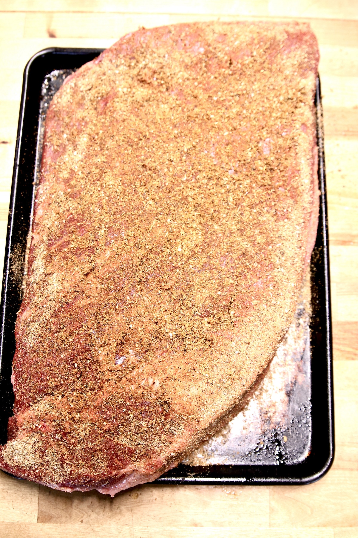 Dry rubbed beef brisket on a sheet pan ready to smoke.