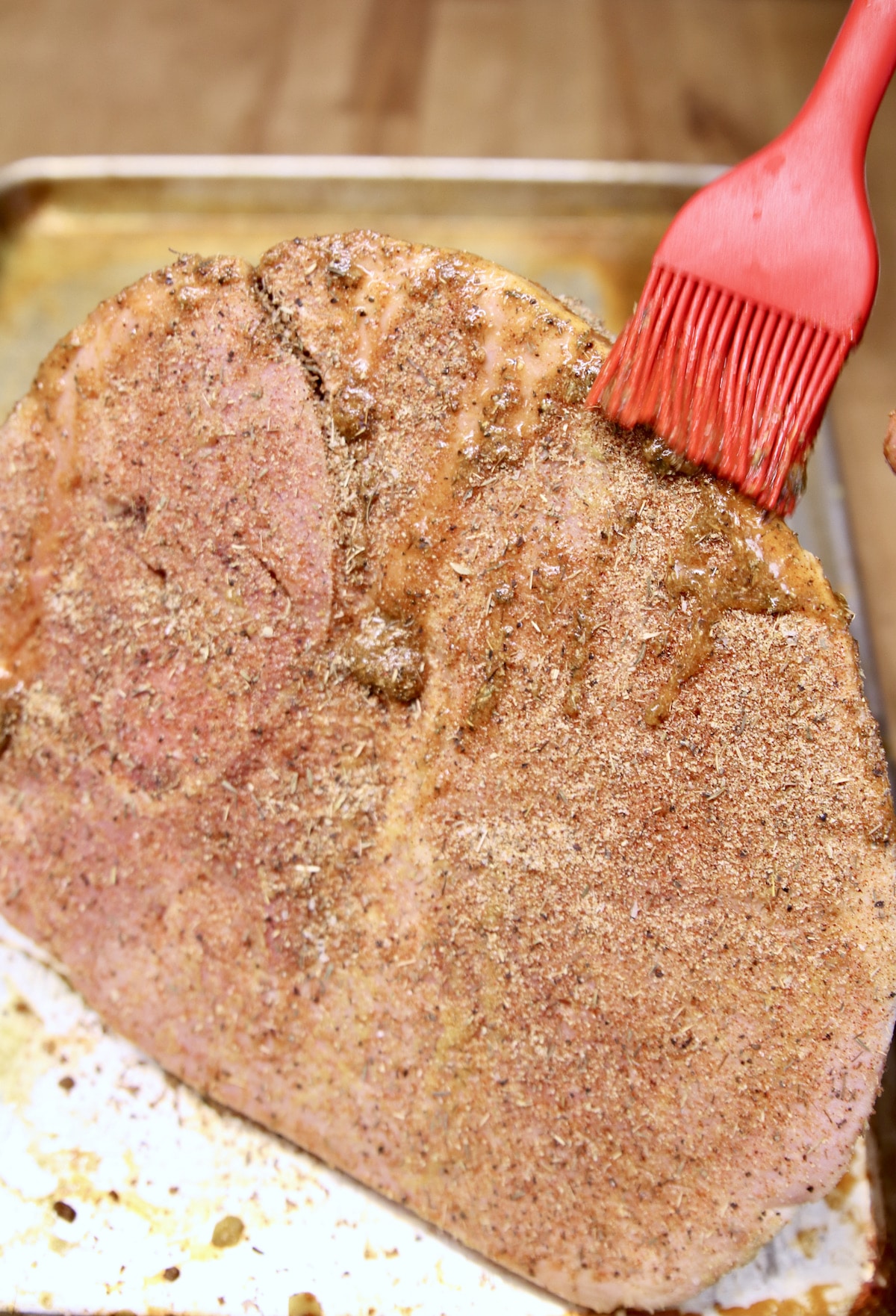 brushing ham with marinade and dry rub.