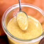 spoonful of honey mustard sauce dipping from a jar.