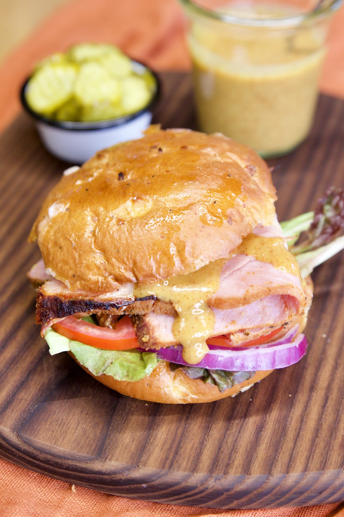 Ham sandwich on a bun with lettuce, tomato, onion and honey mustard.