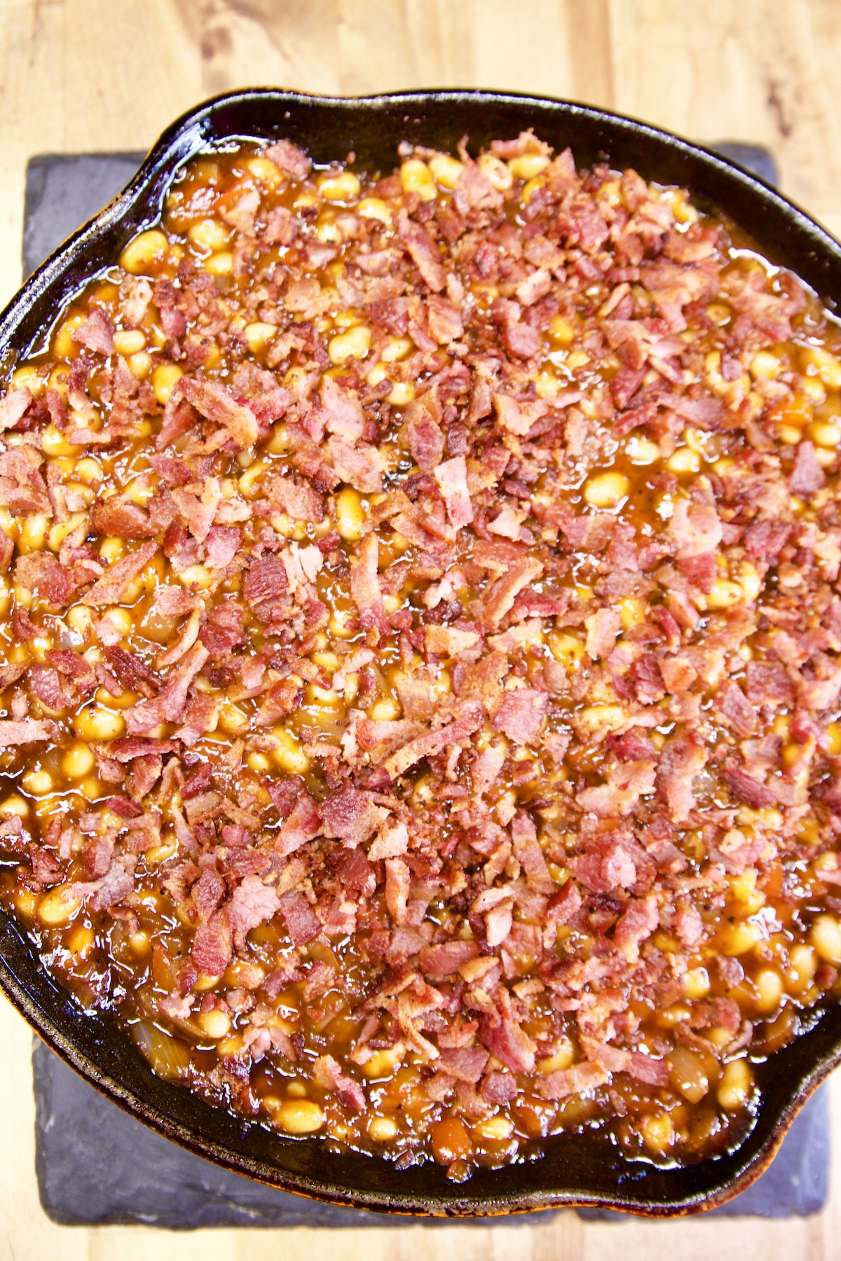 Skillet of baked beans topped with bacon.