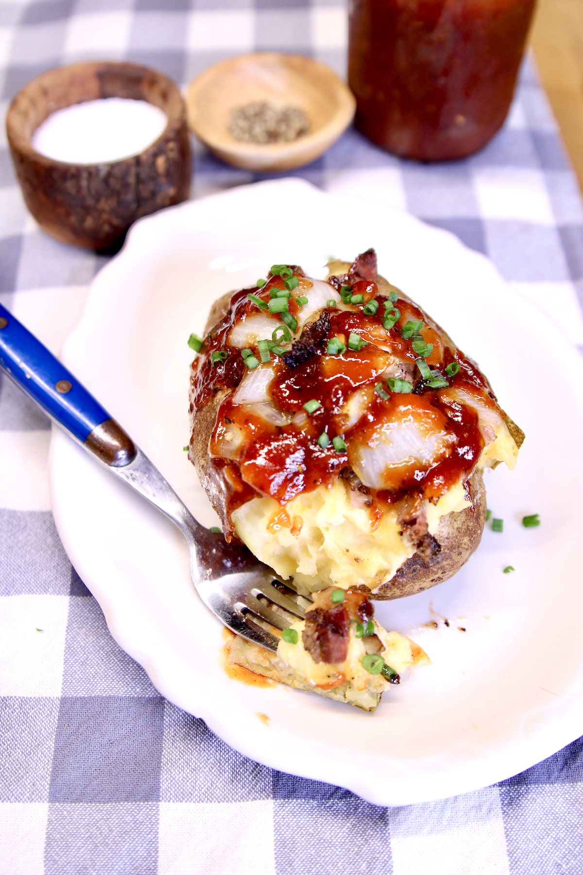 Twice baked potato on a plate with bite on a fork.