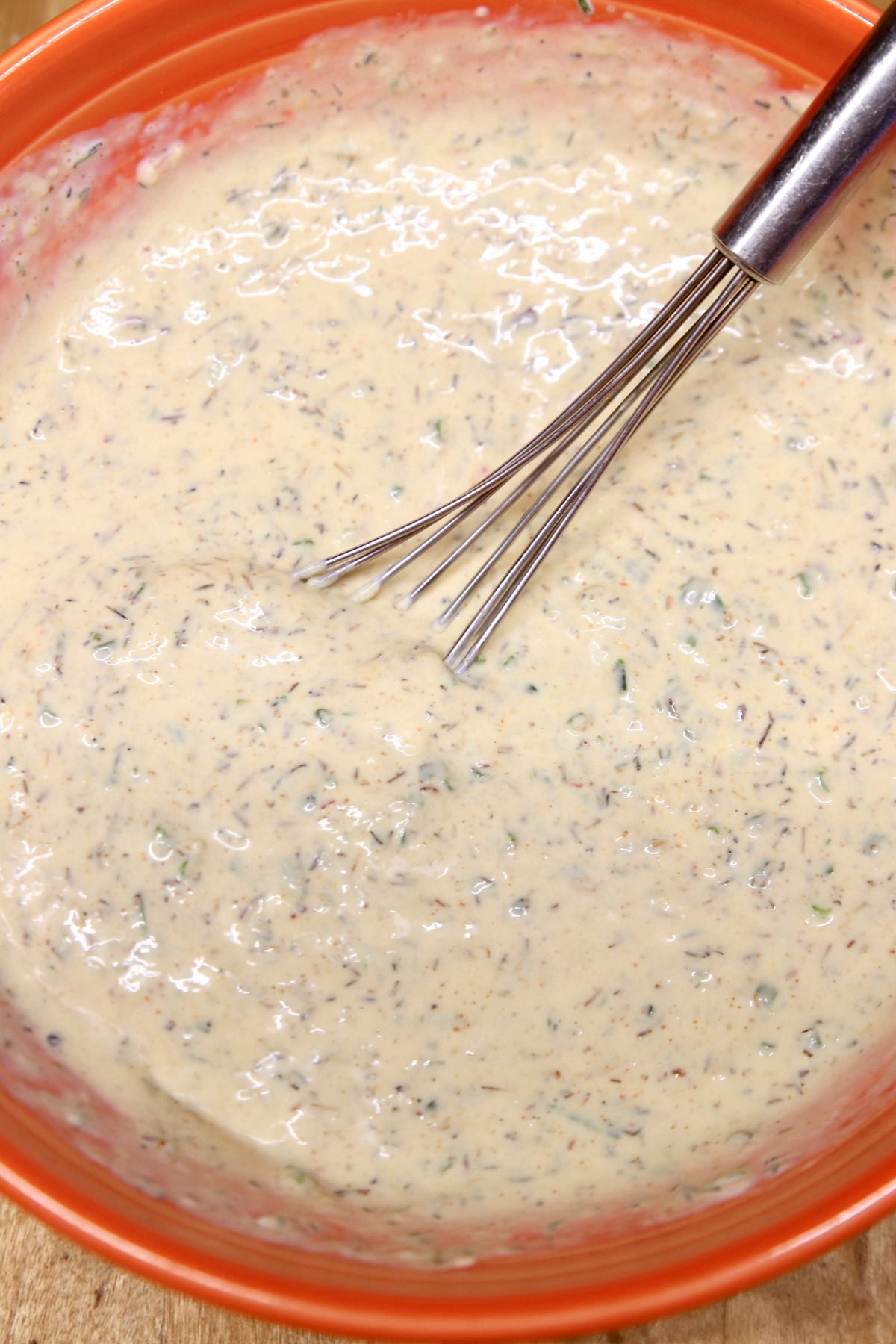 Bowl of garlic cream sauce with whisk.