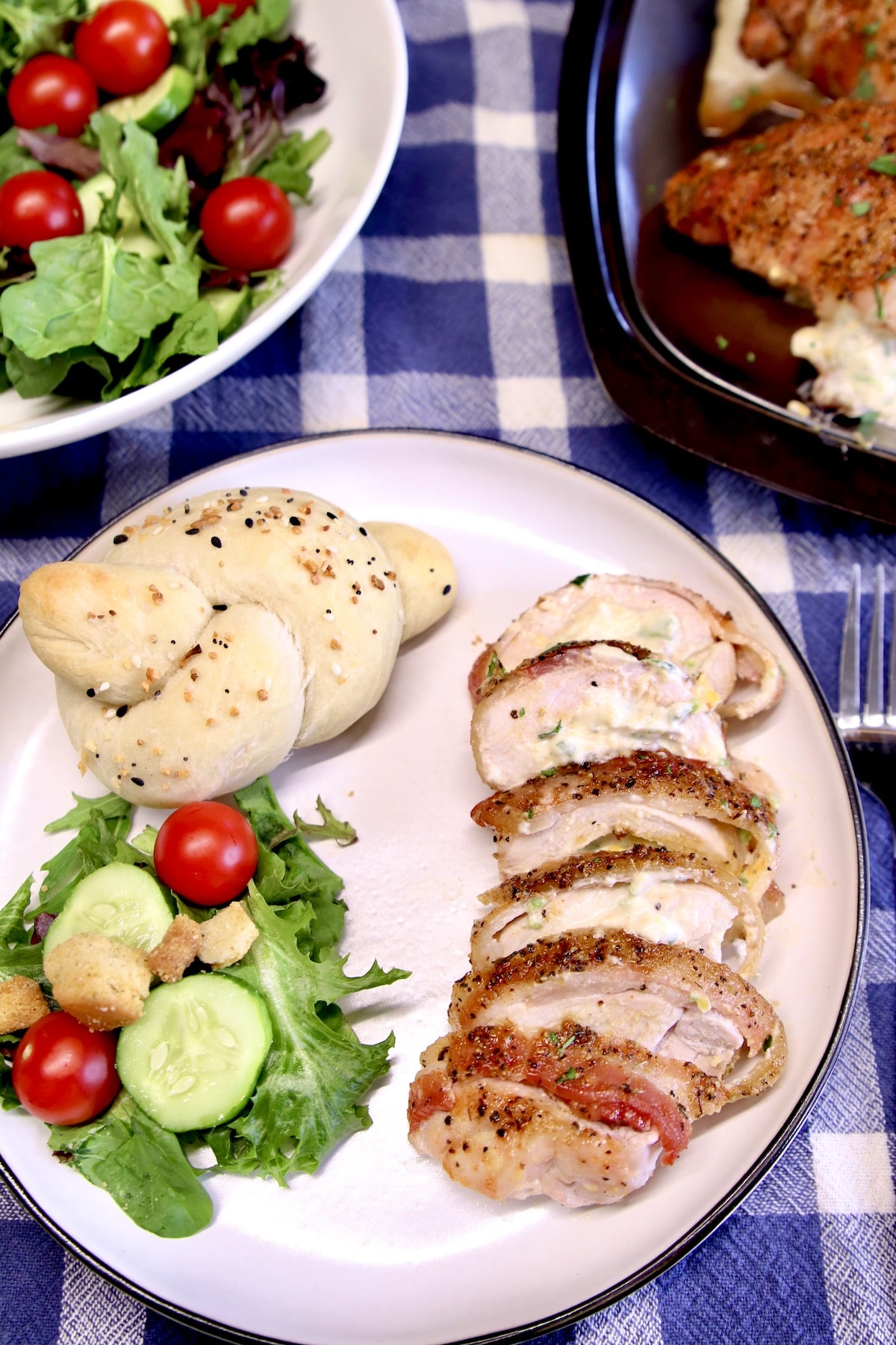 Plate of sliced pork chop, salad, bread.