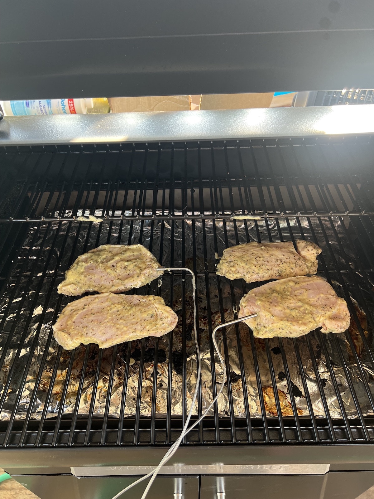 4 pork chops on a grill with meat probes.