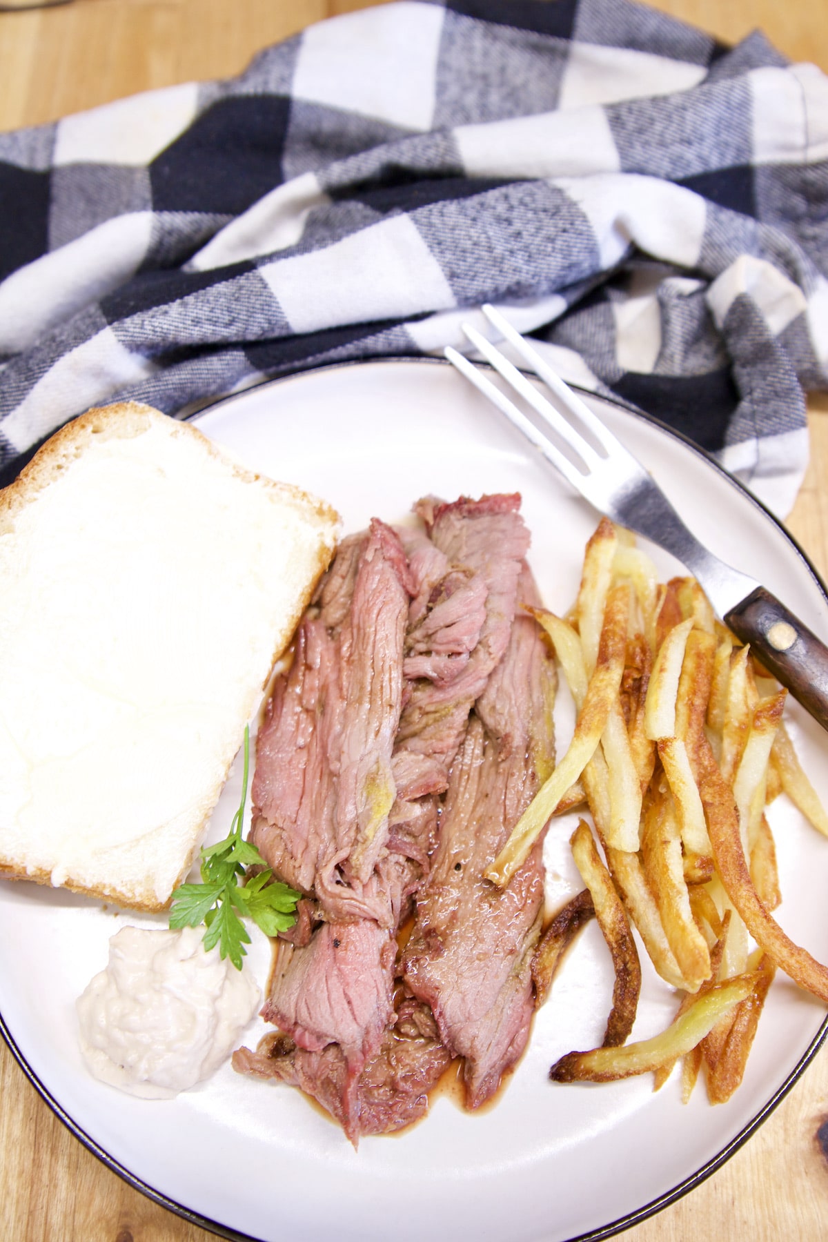 Plate with slice of white bread, sliced roast beef, french fries.