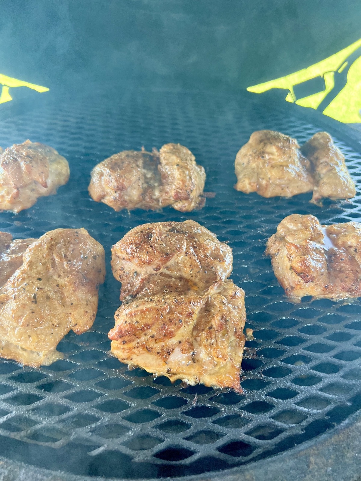 Smoky chicken thighs on a grill.