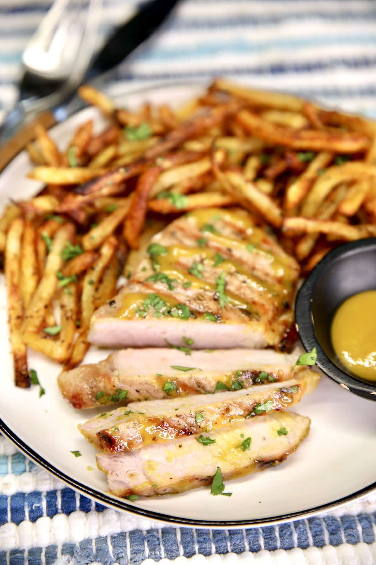 Sliced pork chop on a plate with fries.