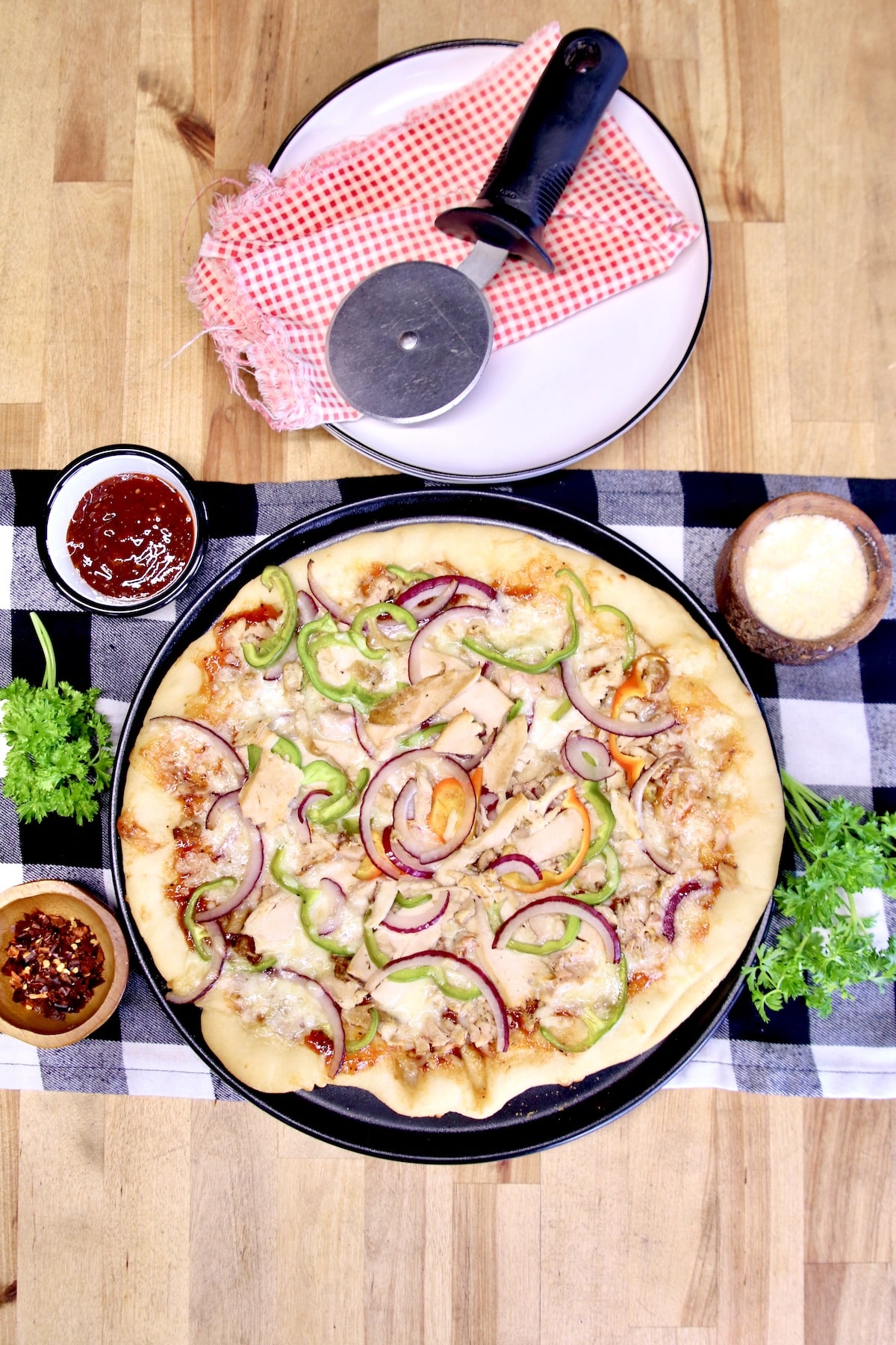 BBQ Chicken pizza on a round pan with plates.