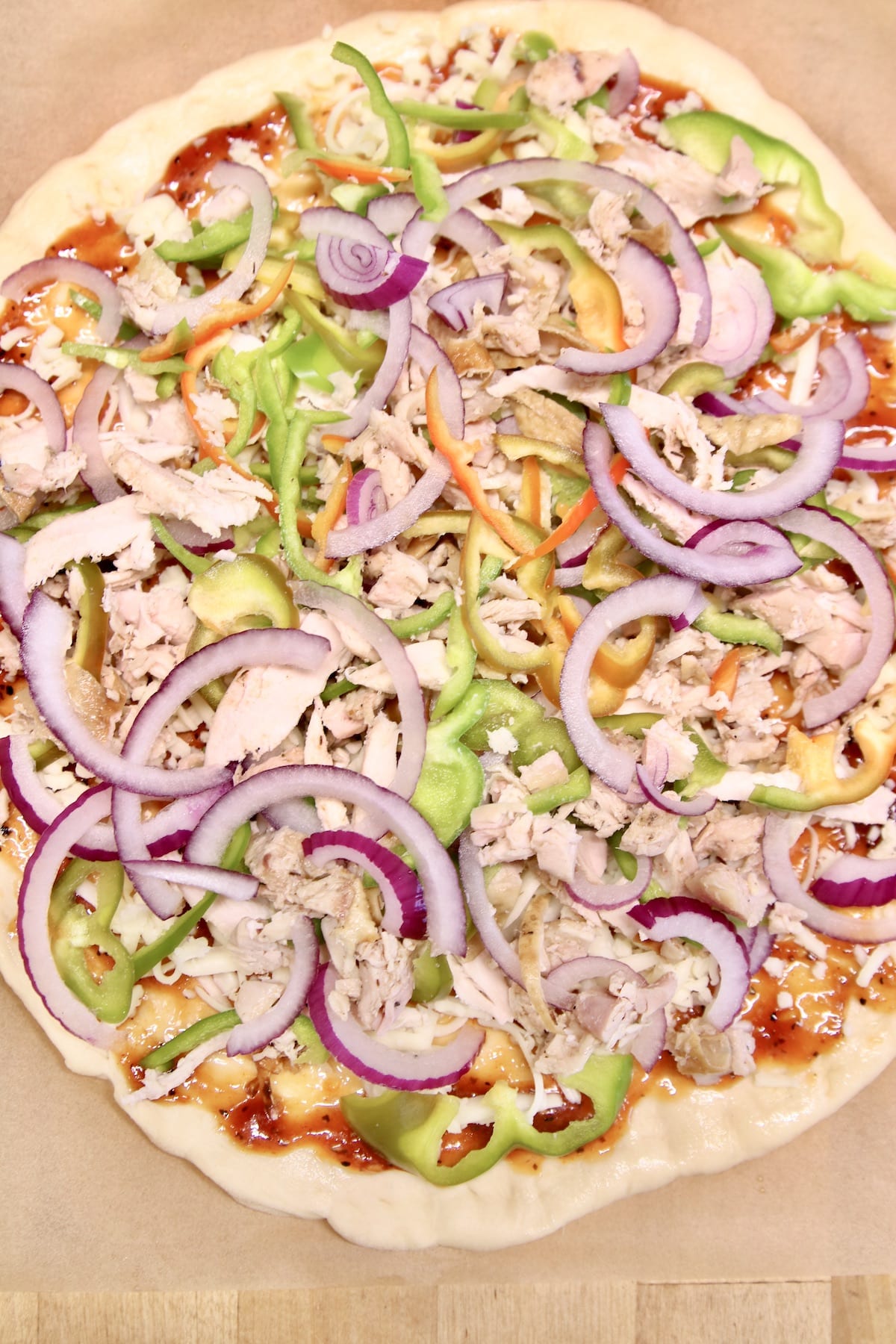 Pizza with chicken, red onion, peppers, ready to cook.