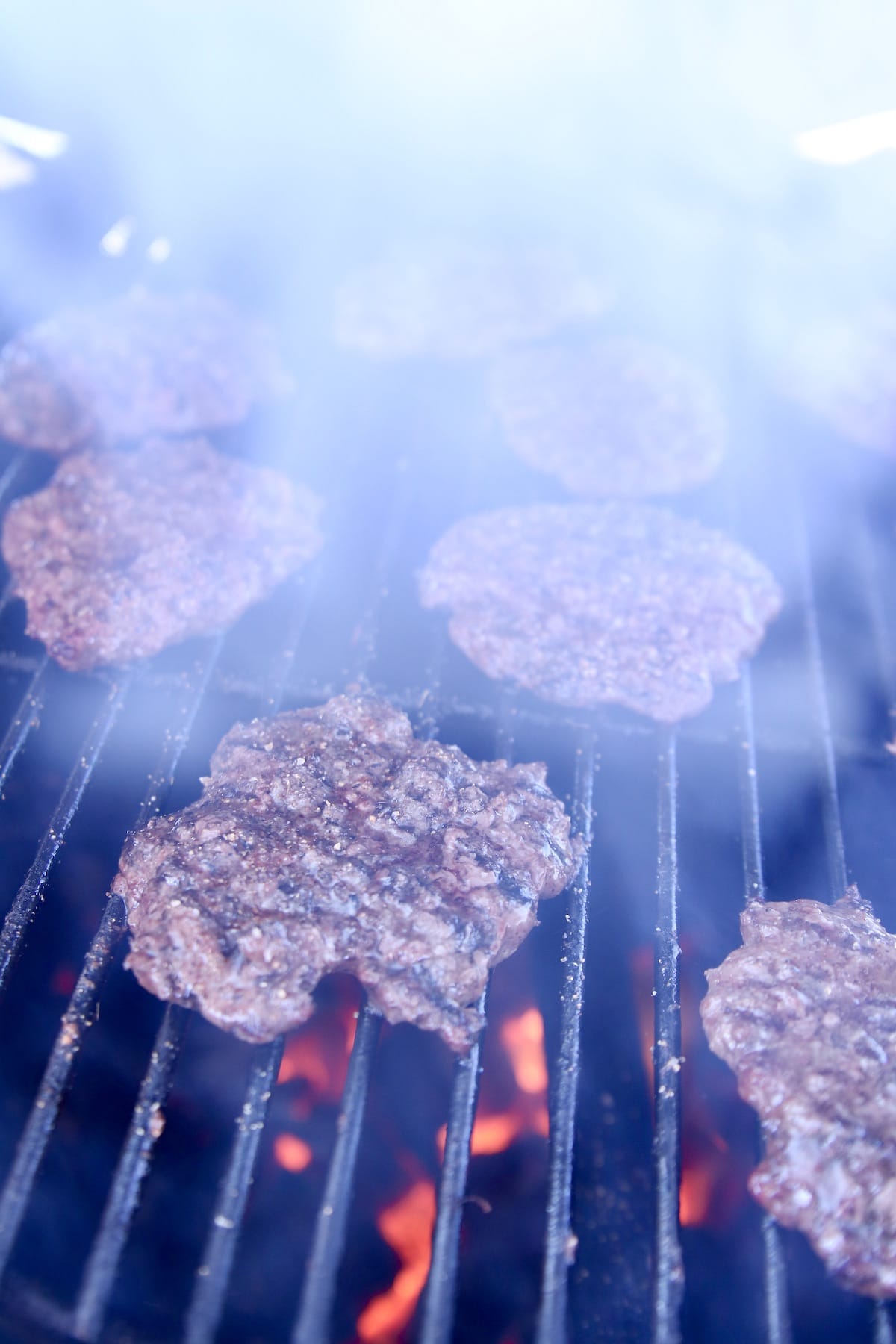 Smoky grill fire with burger patties.