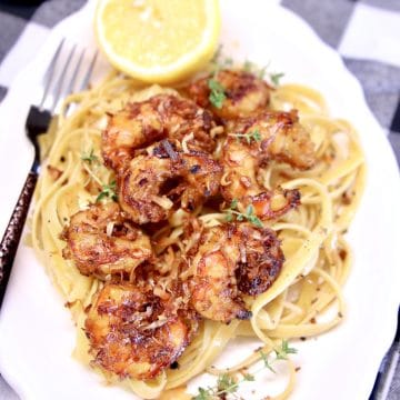 Platter of pasta and shrimp with half of a lemon.