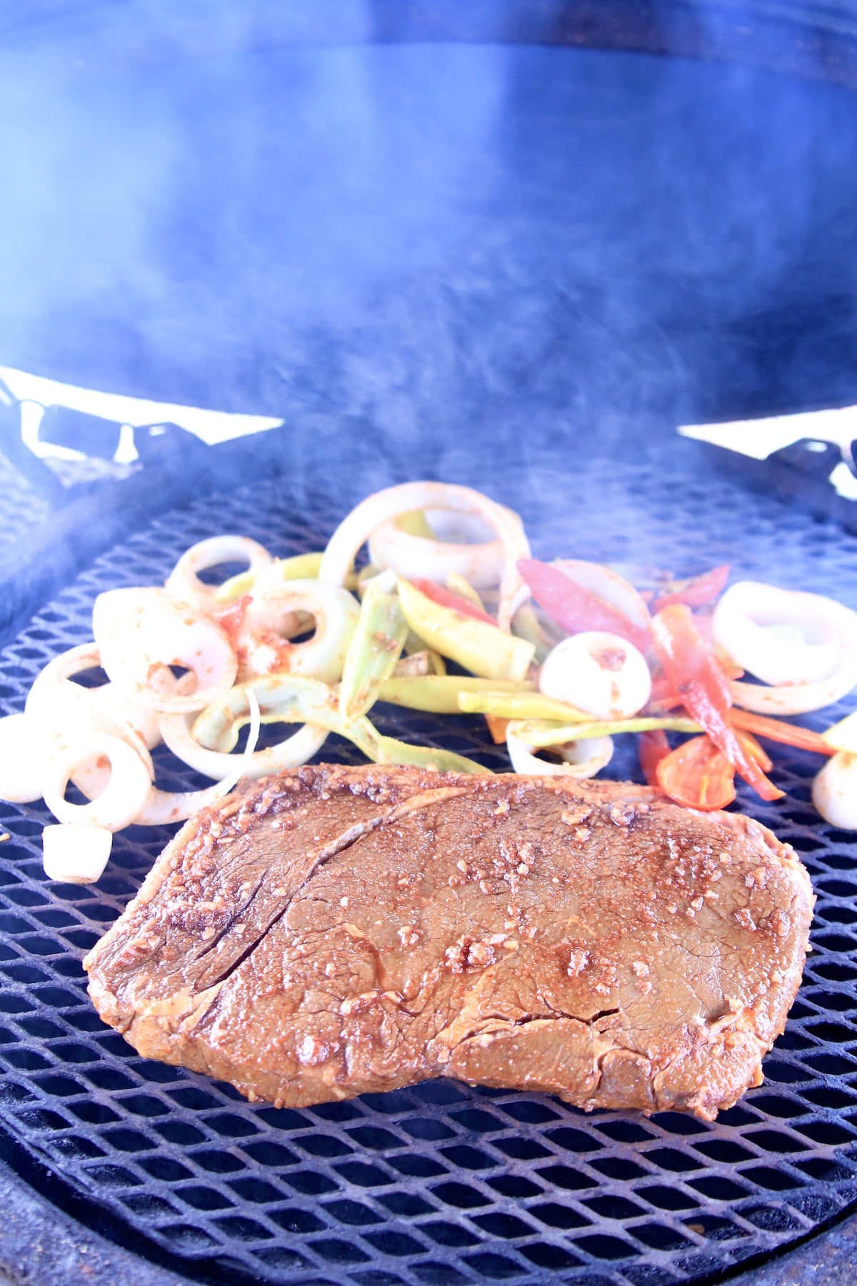 Grilling sirloin steak with peppers and onions.