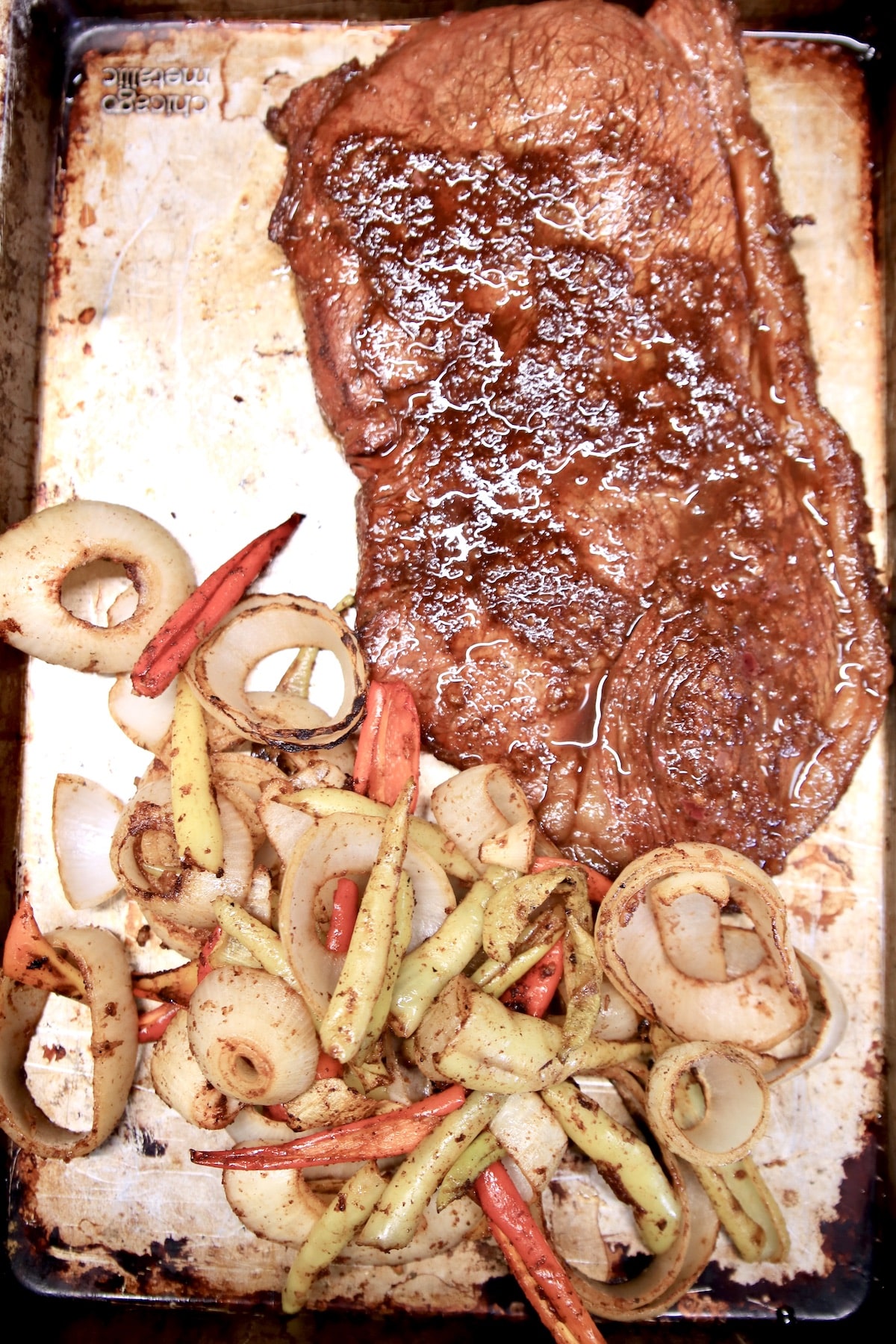Grilled steak, onions and peppers on a baking sheet.
