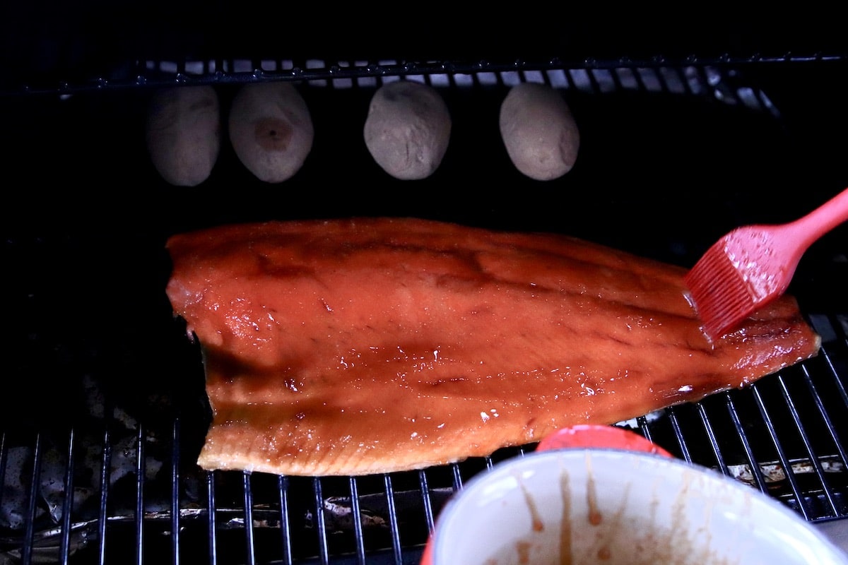Brushing glaze over grilled salmon fillet.