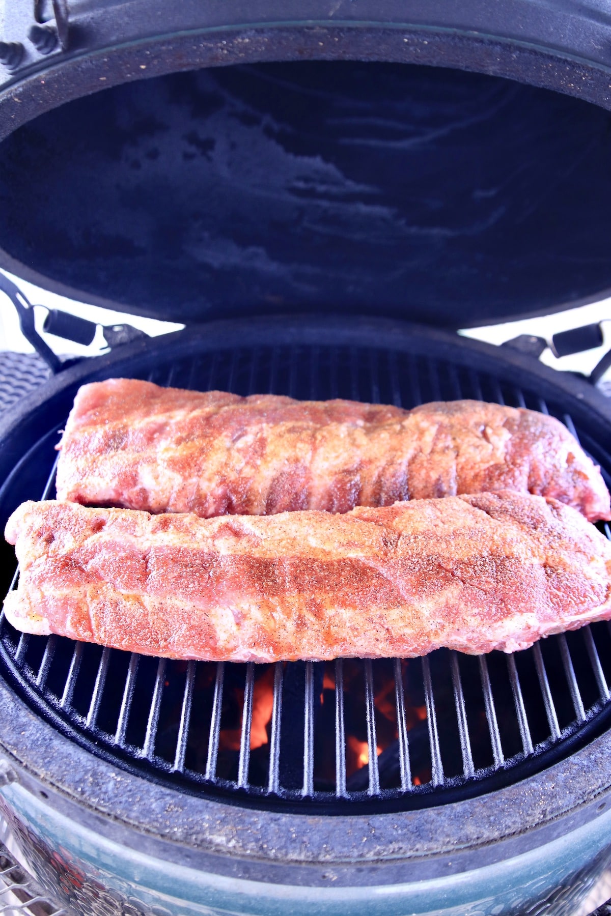 2 racks baby back ribs on a grill.