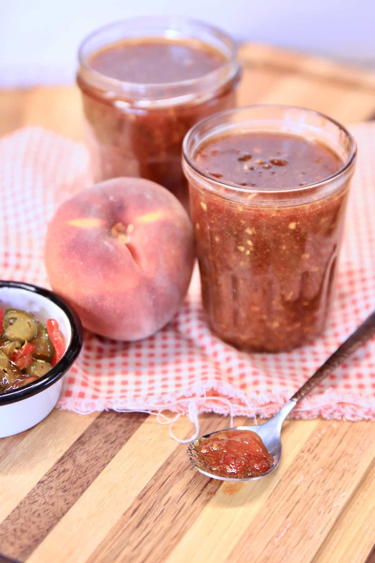 2 jars of bbq sauce with whole peach, spoonful of sauce.