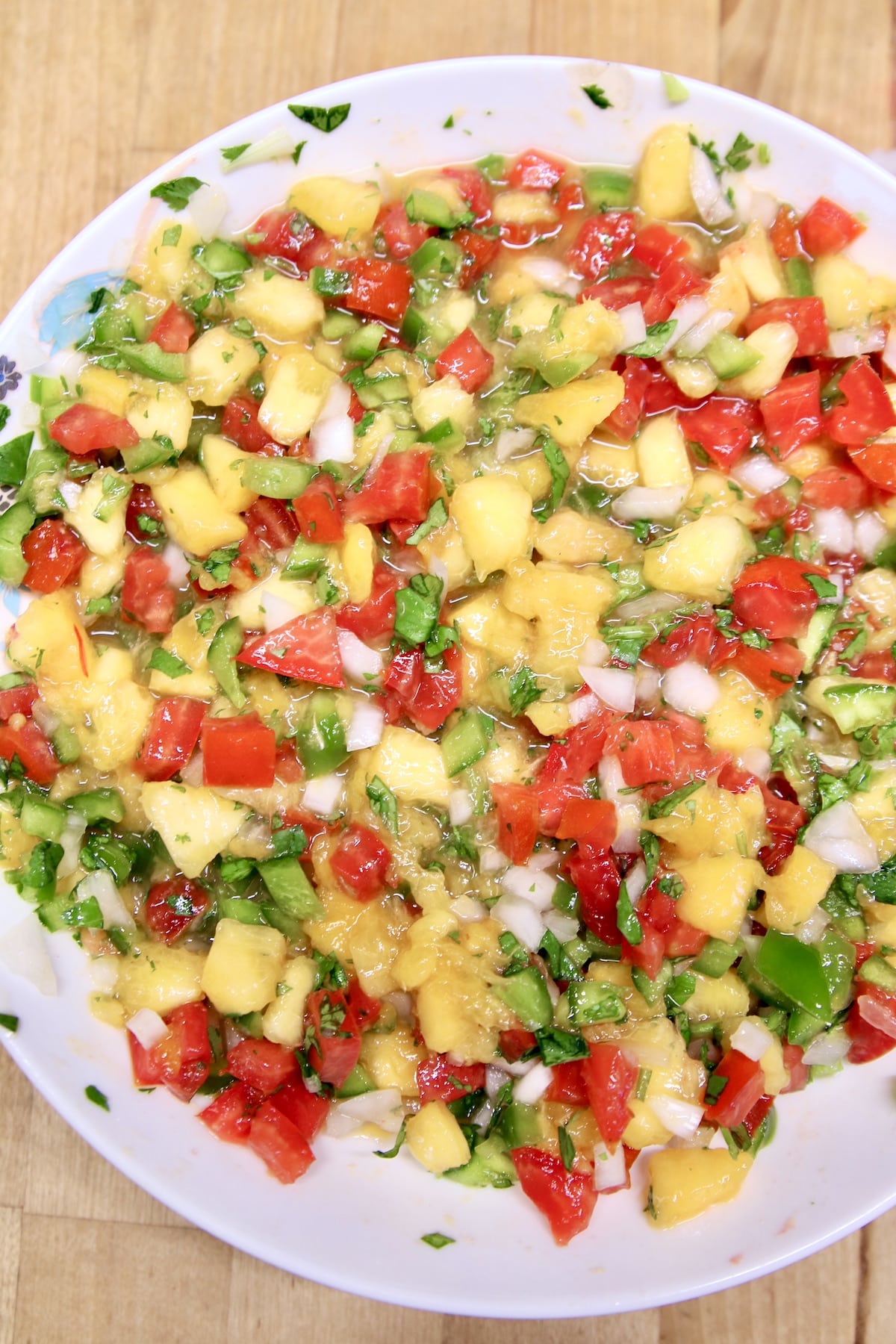 Bowl of peach salsa with tomatoes and cilantro.