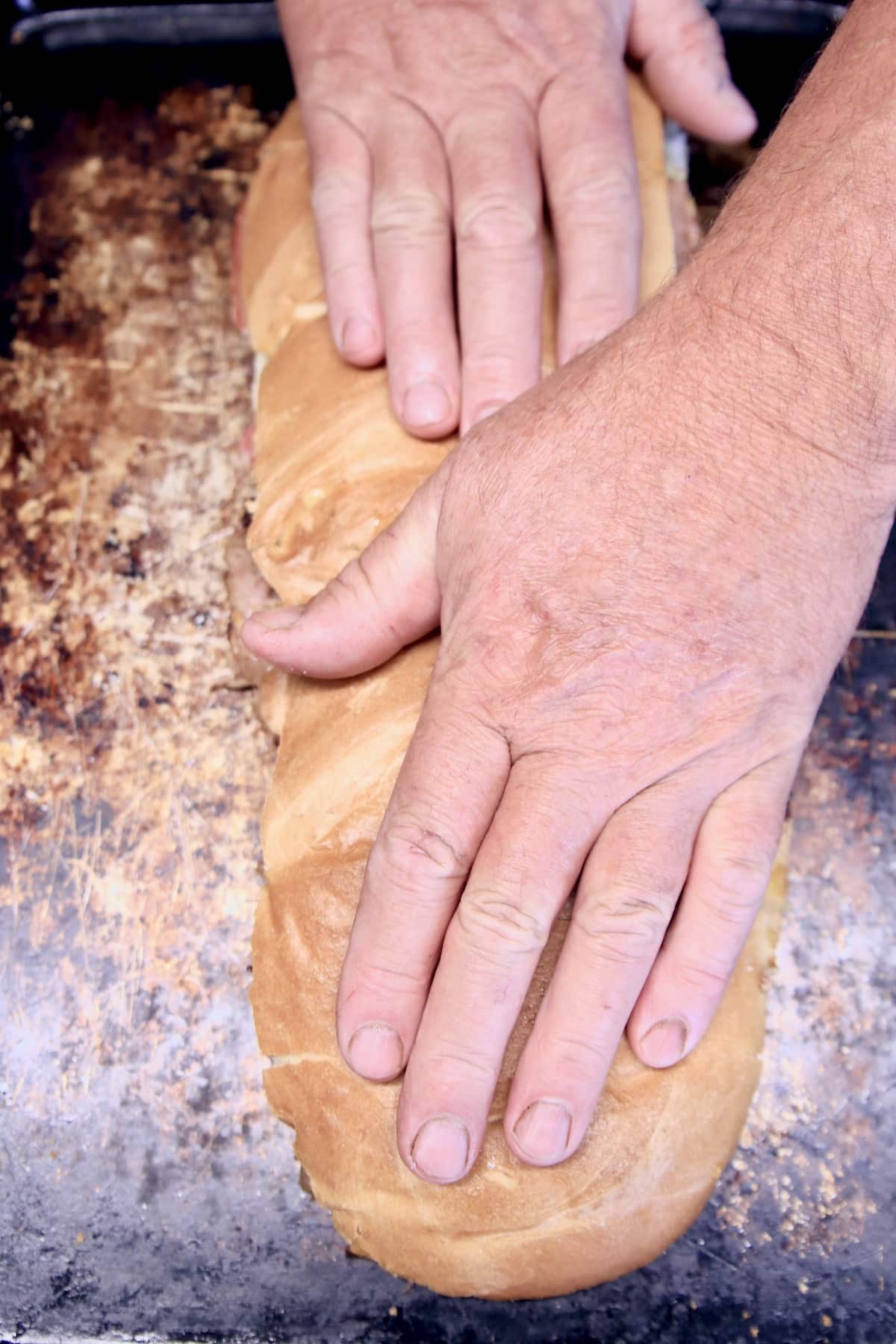 Smashing Italian loaf sandwich with hands.