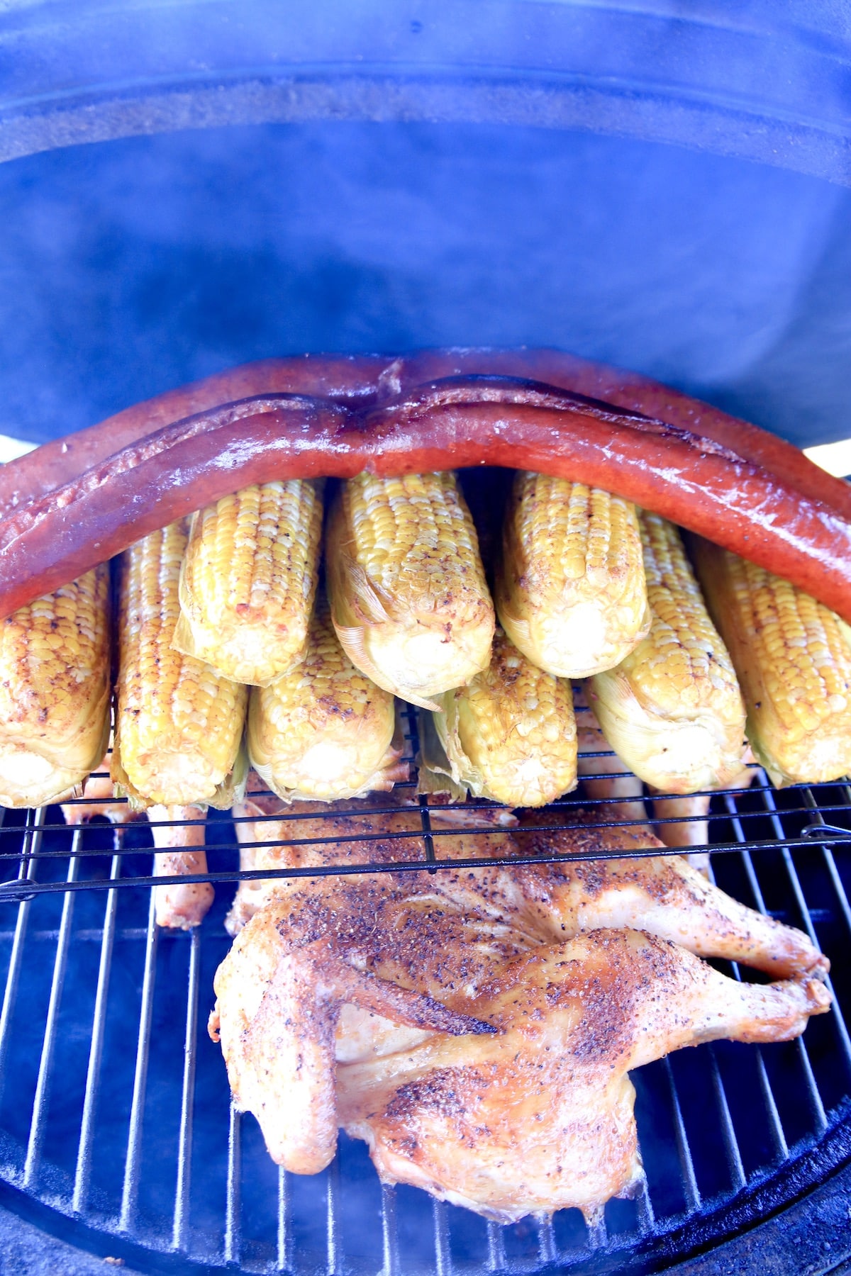 Smoky grill with chicken, corn on the cob, smoked sausage.
