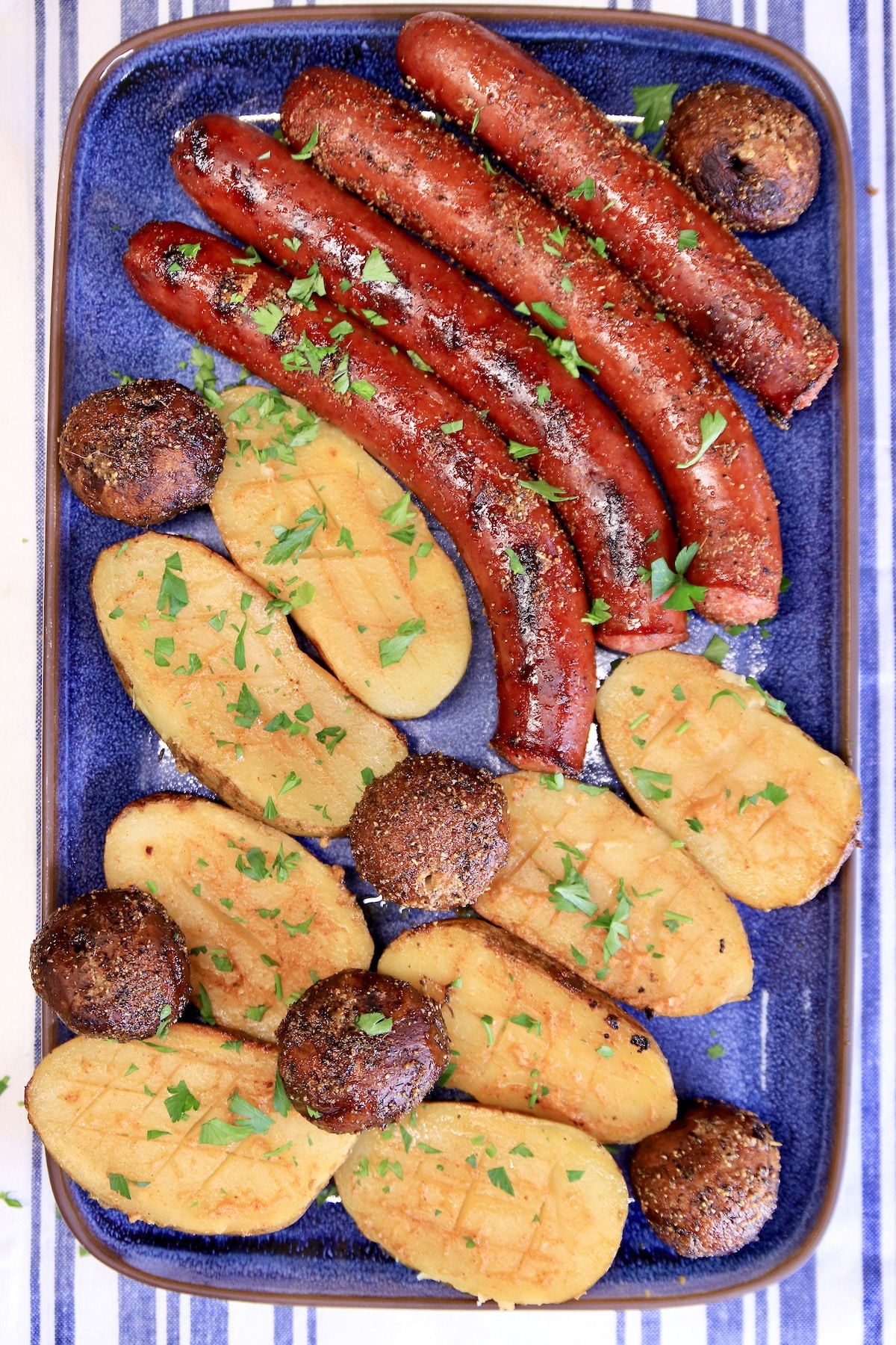 Grilled smoked sausage, potatoes, mushrooms on a platter.