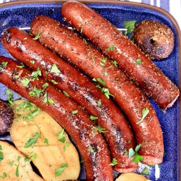 Grilled Smoked Sausage links with potatoes on a blue platter.