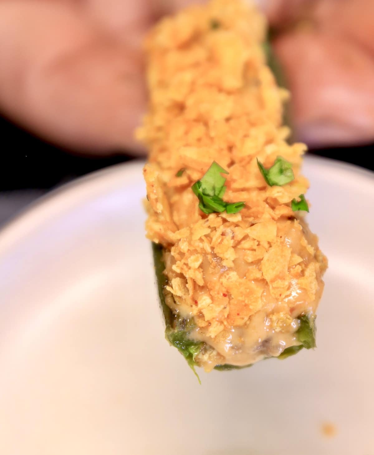 Closeup of Doritos Nacho Cheese Jalapeno Popper, held in hand.
