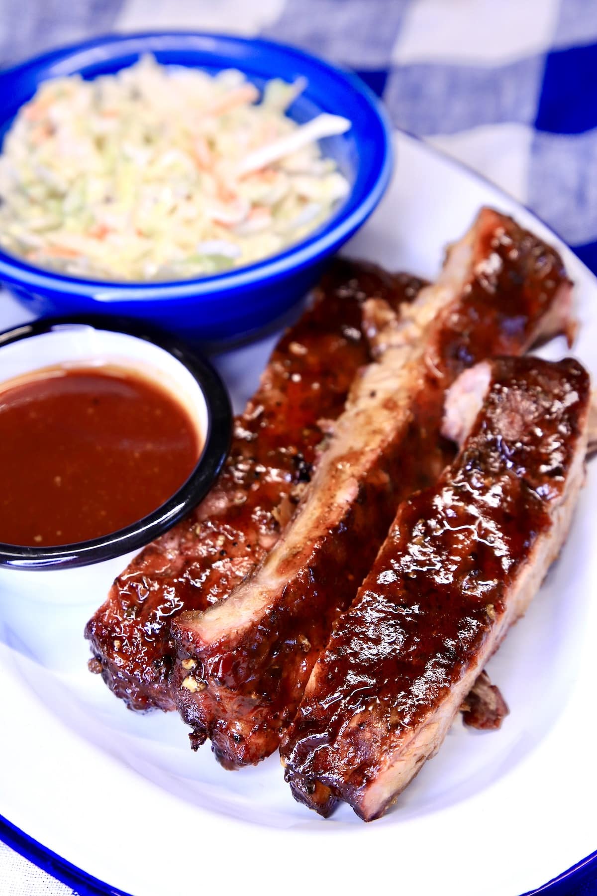 Platter of ribs with sauce and slaw.