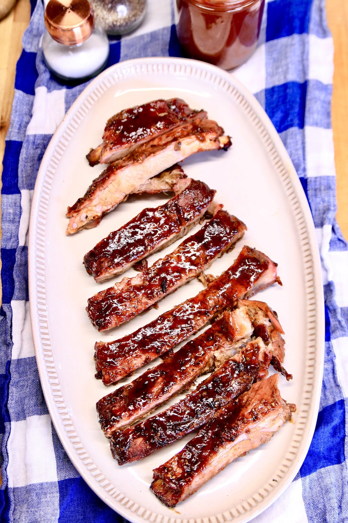 Platter of bbq spare ribs on a blue check cloth.