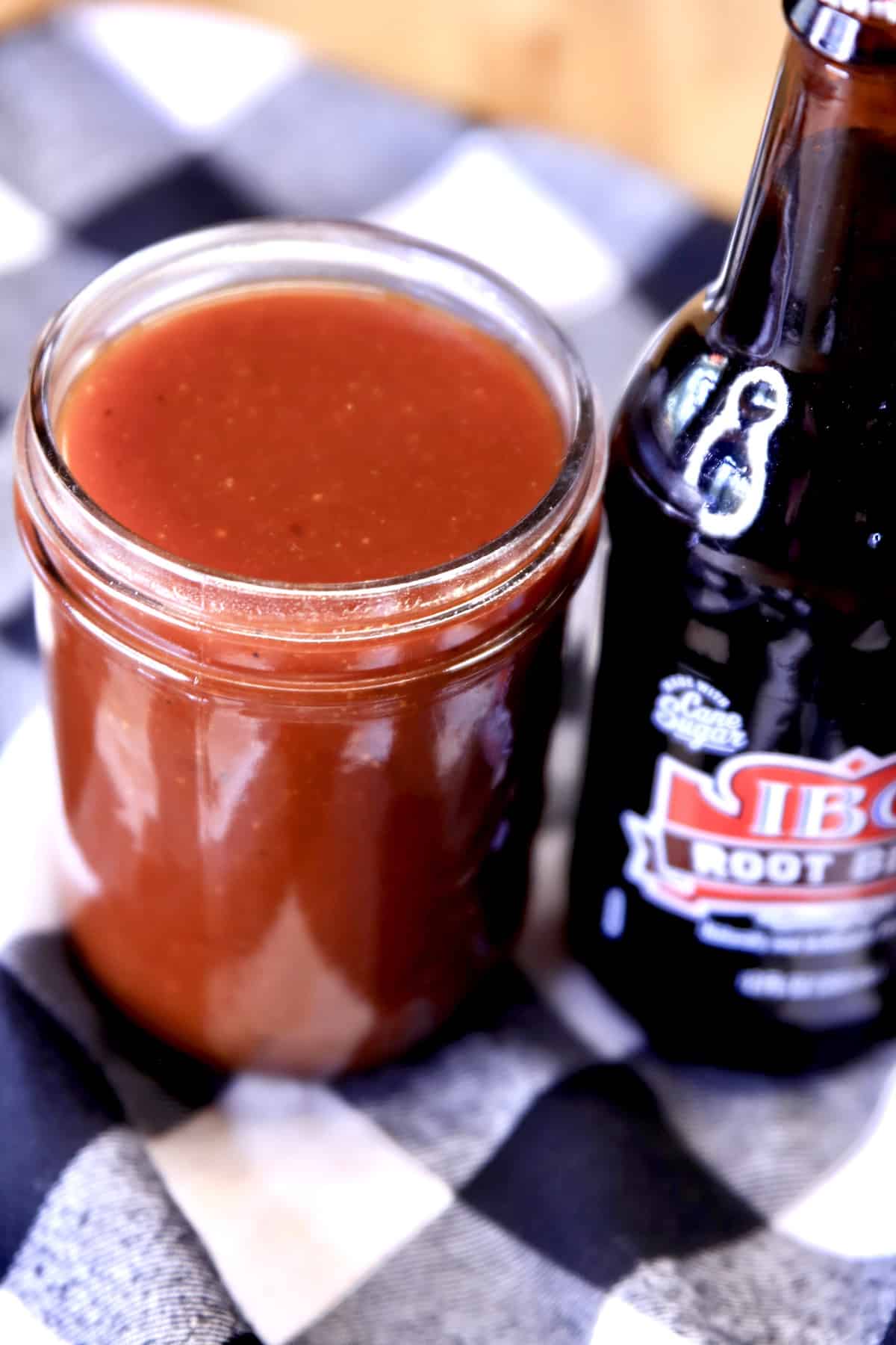 Jar of bbq sauce with bottle of root beer.
