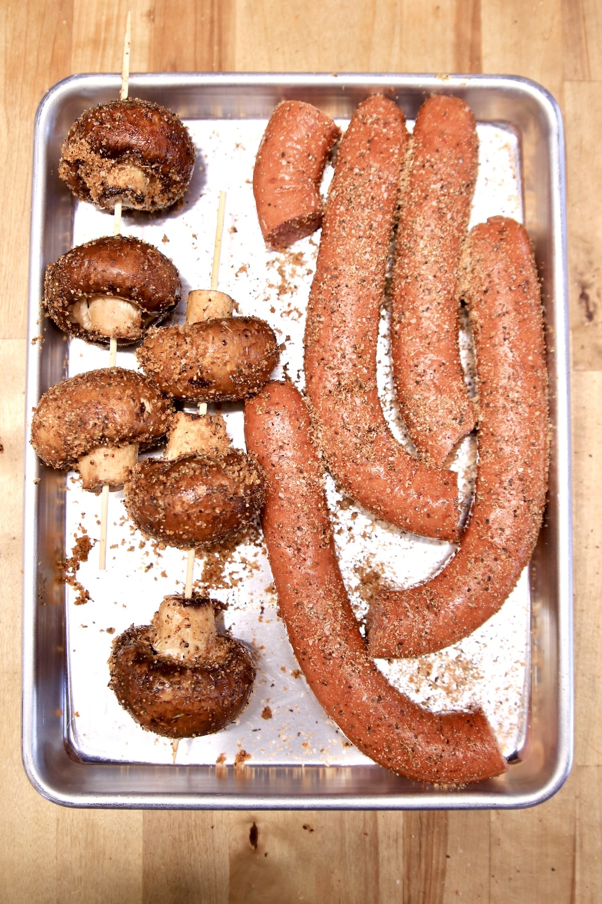 Smoked sausage links and mushrooms on a sheet pan.