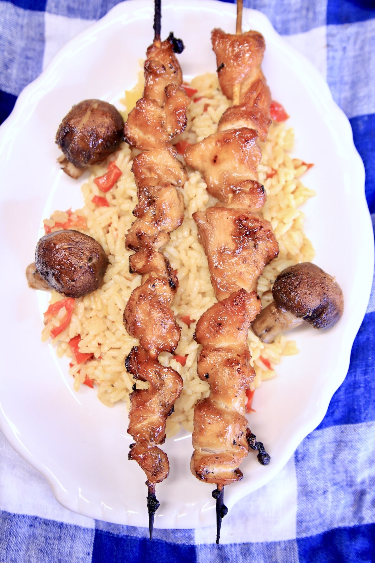 Plate of rice, chicken skewers and mushrooms.