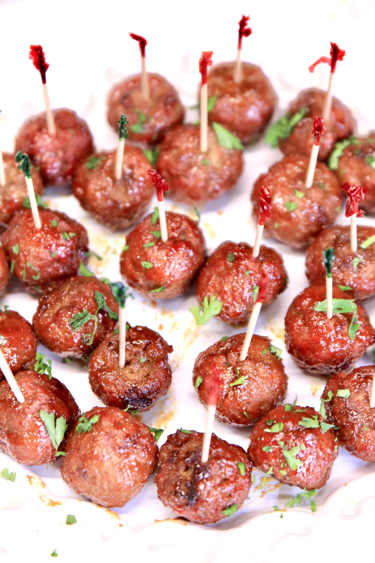 Grilled teriyaki meatballs with appetizer picks on a platter.