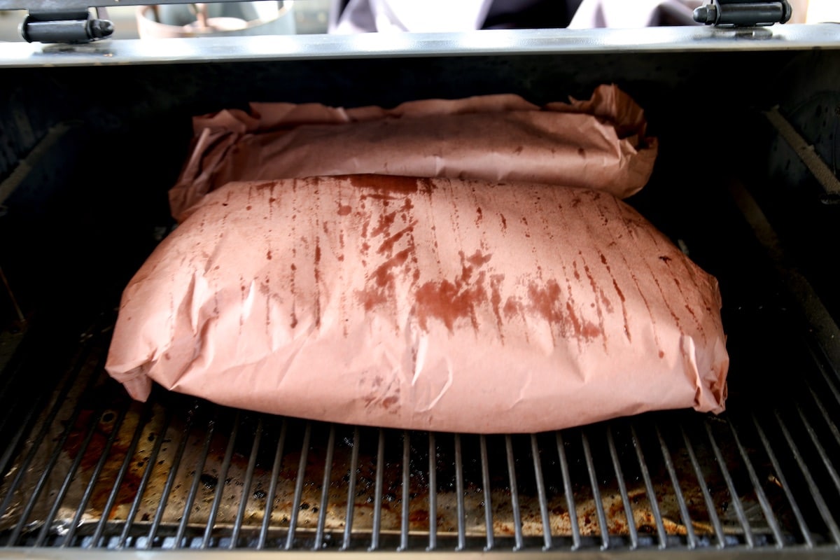 Ribs wrapped in butcher paper on a grill.