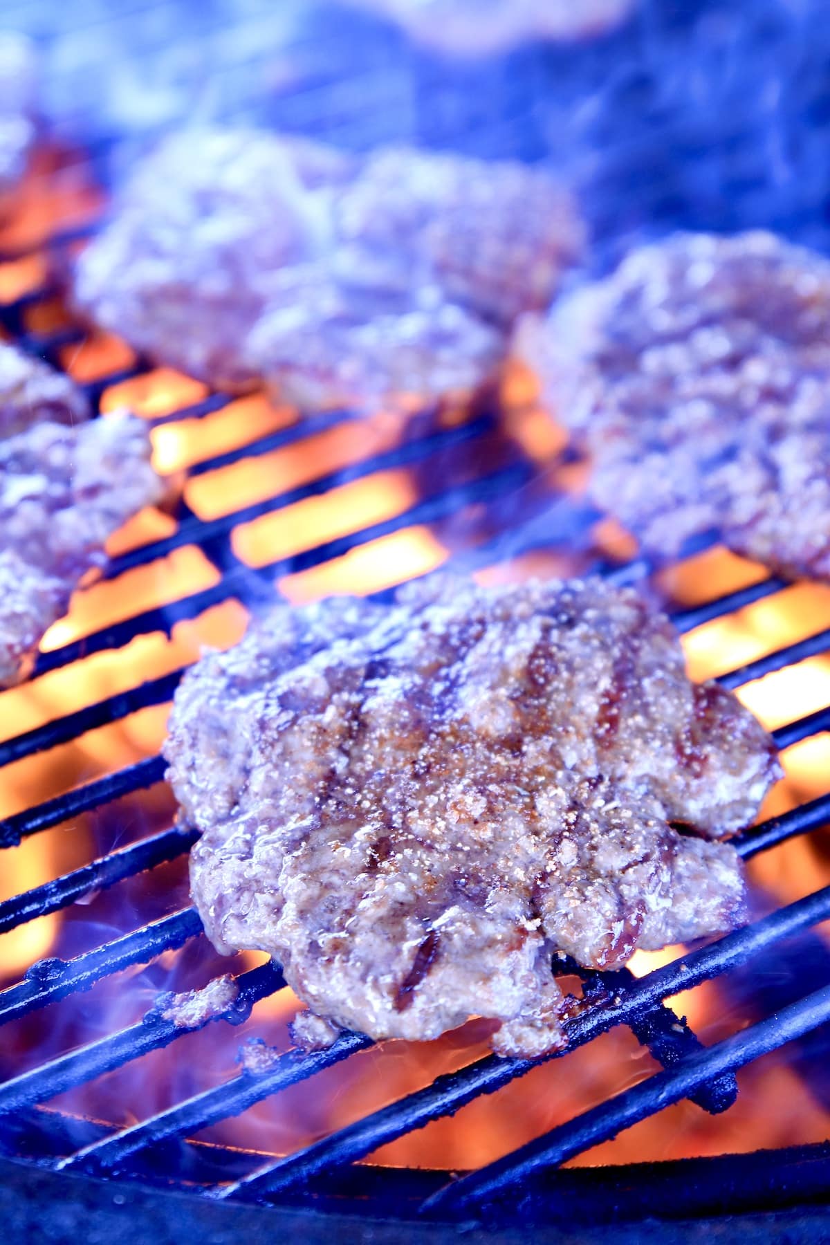 Grilling burger patties over open flame.