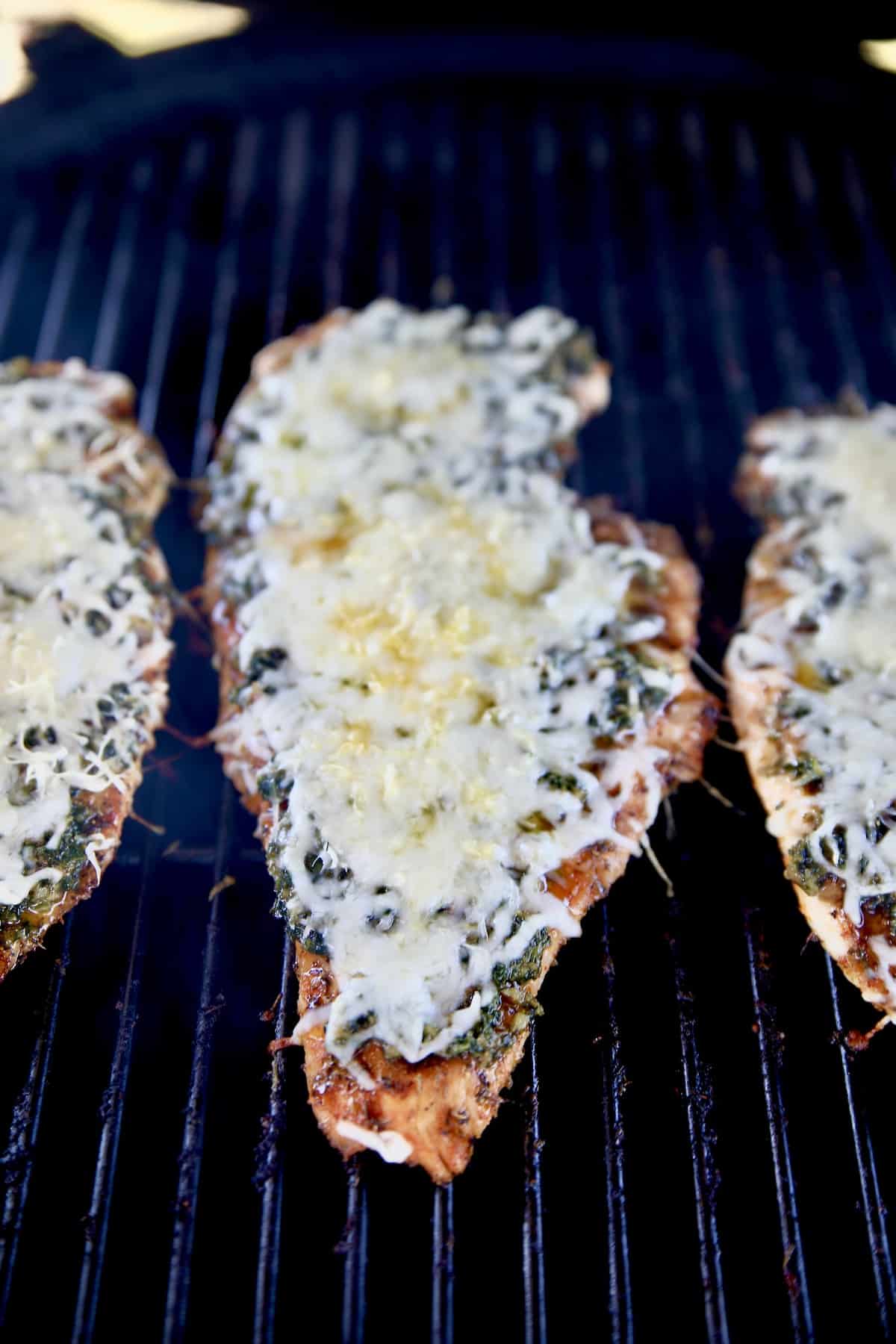 Grilling chicken with cheese melted over the top.