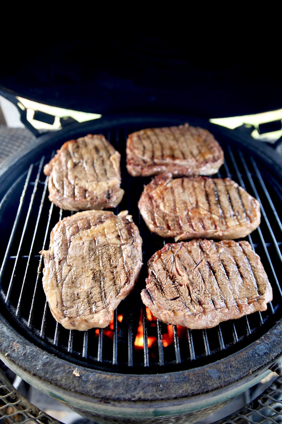 Grilling ribeye steaks on a ceramic grill.
