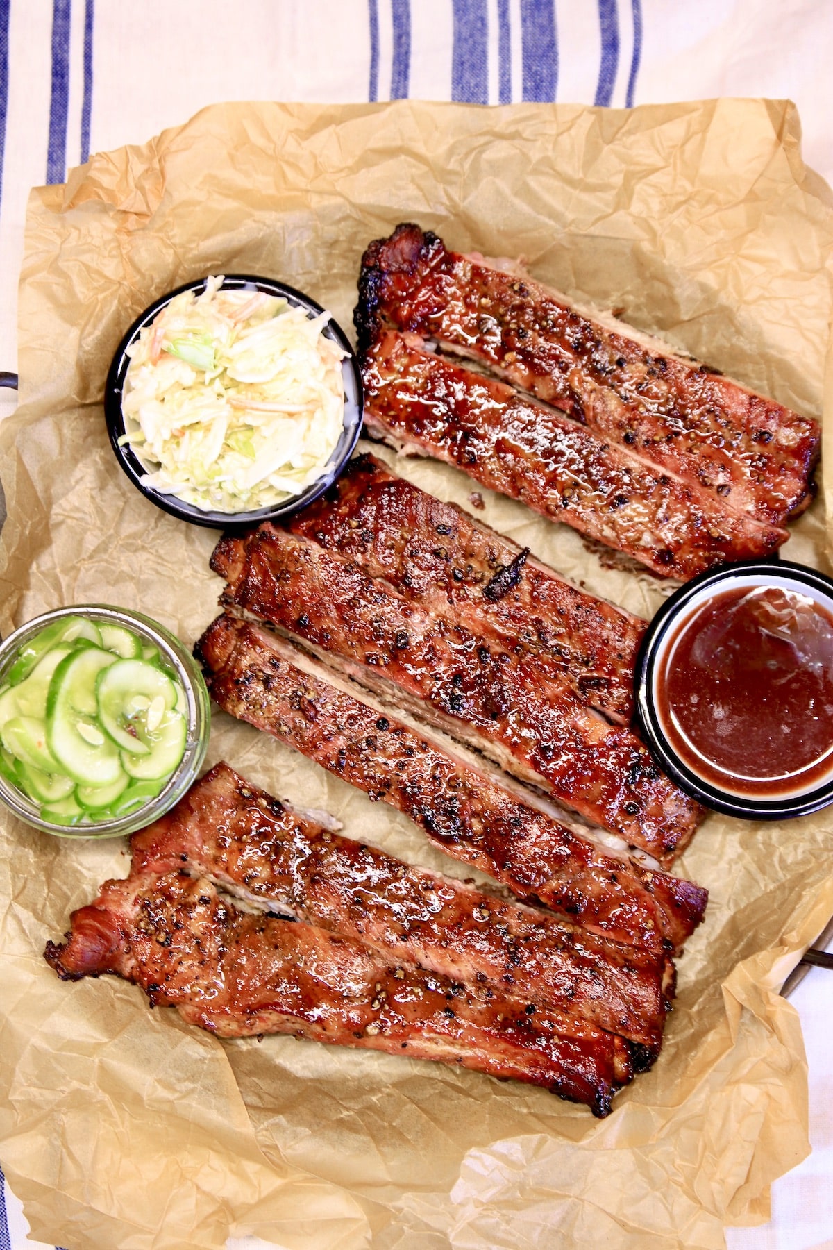 Platter of spare ribs with bowls of slaw, pickles