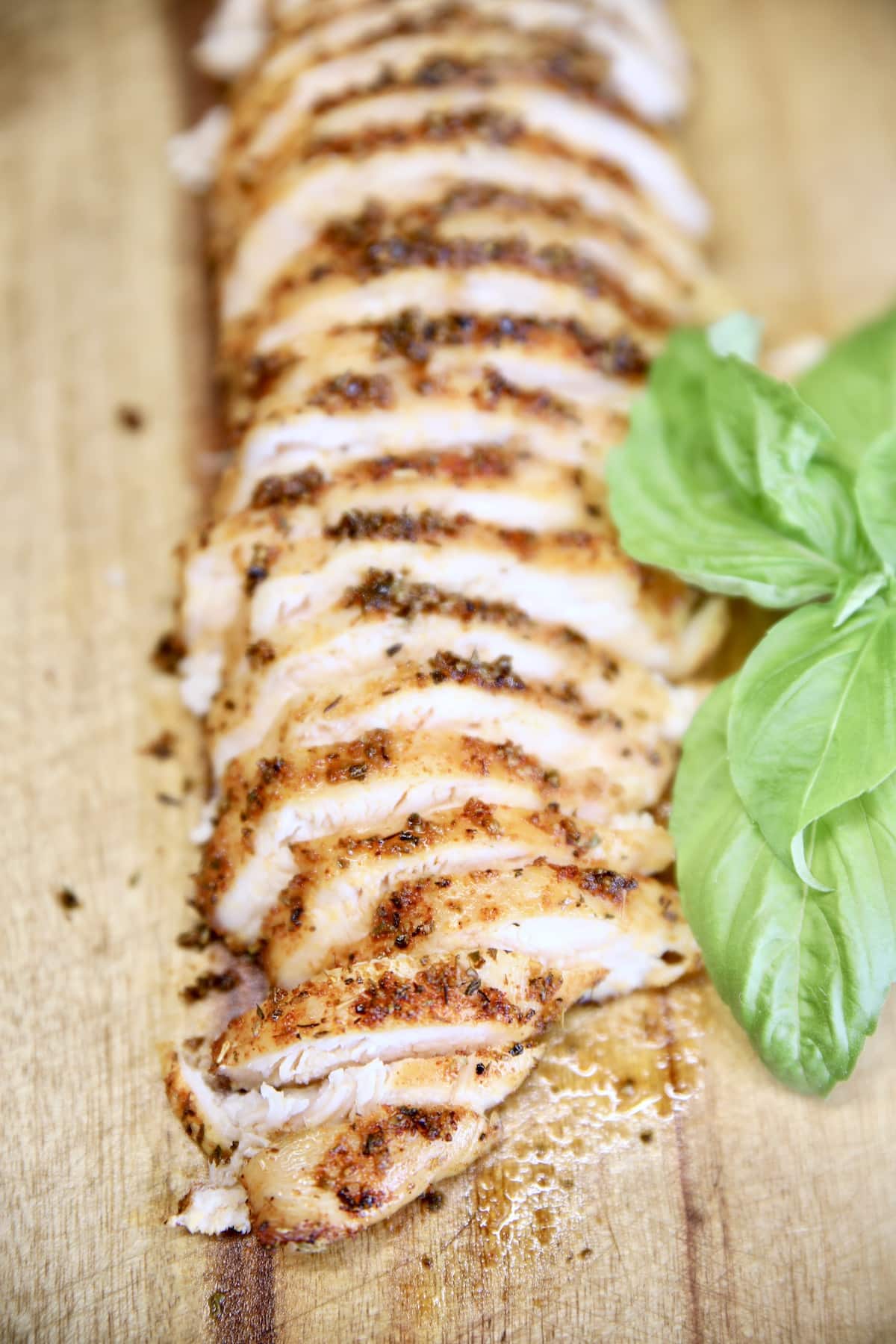 Sliced chicken with fresh basil leaves.