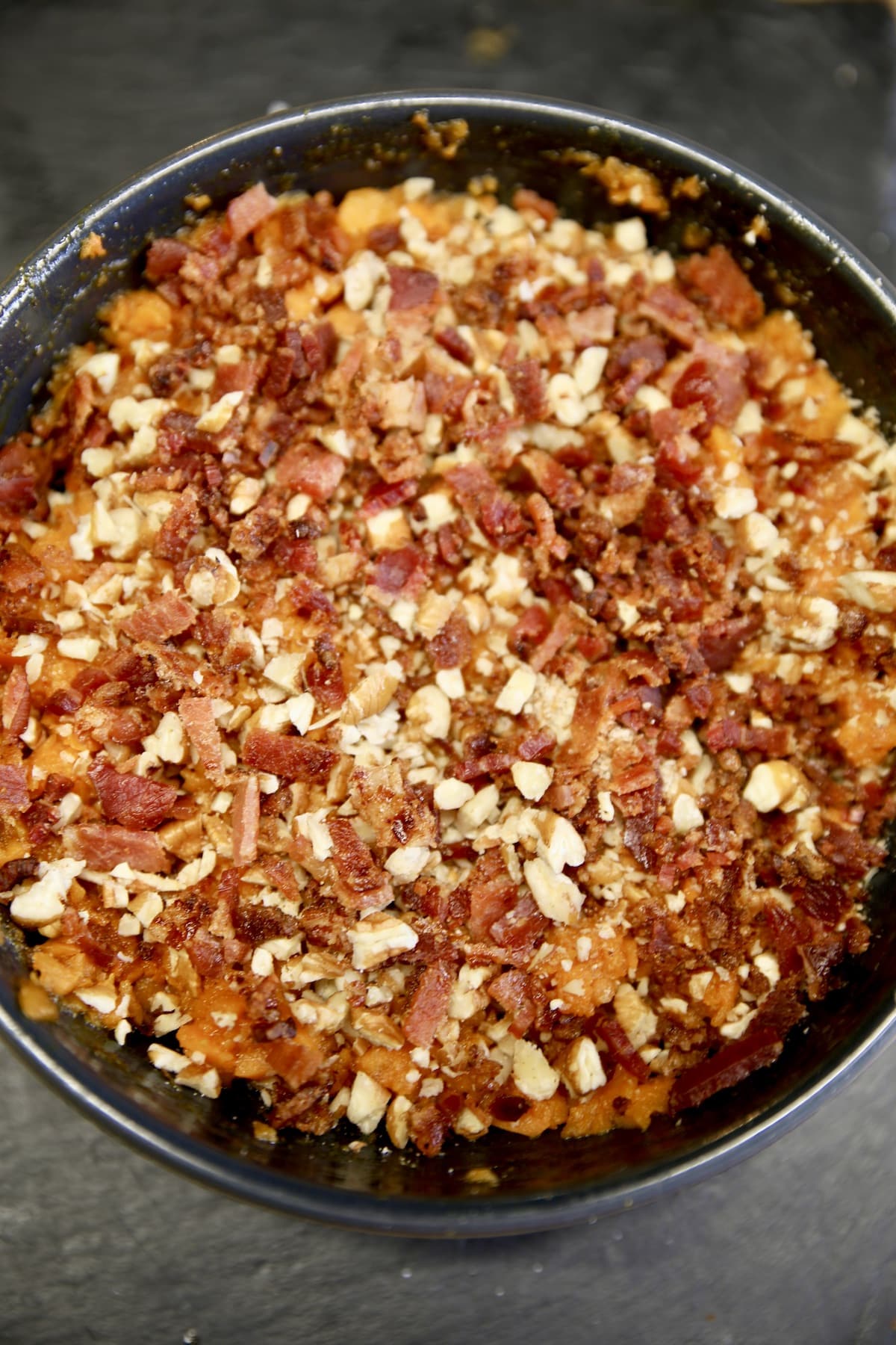 Bowl of sweet potato casserole with bacon and pecans.