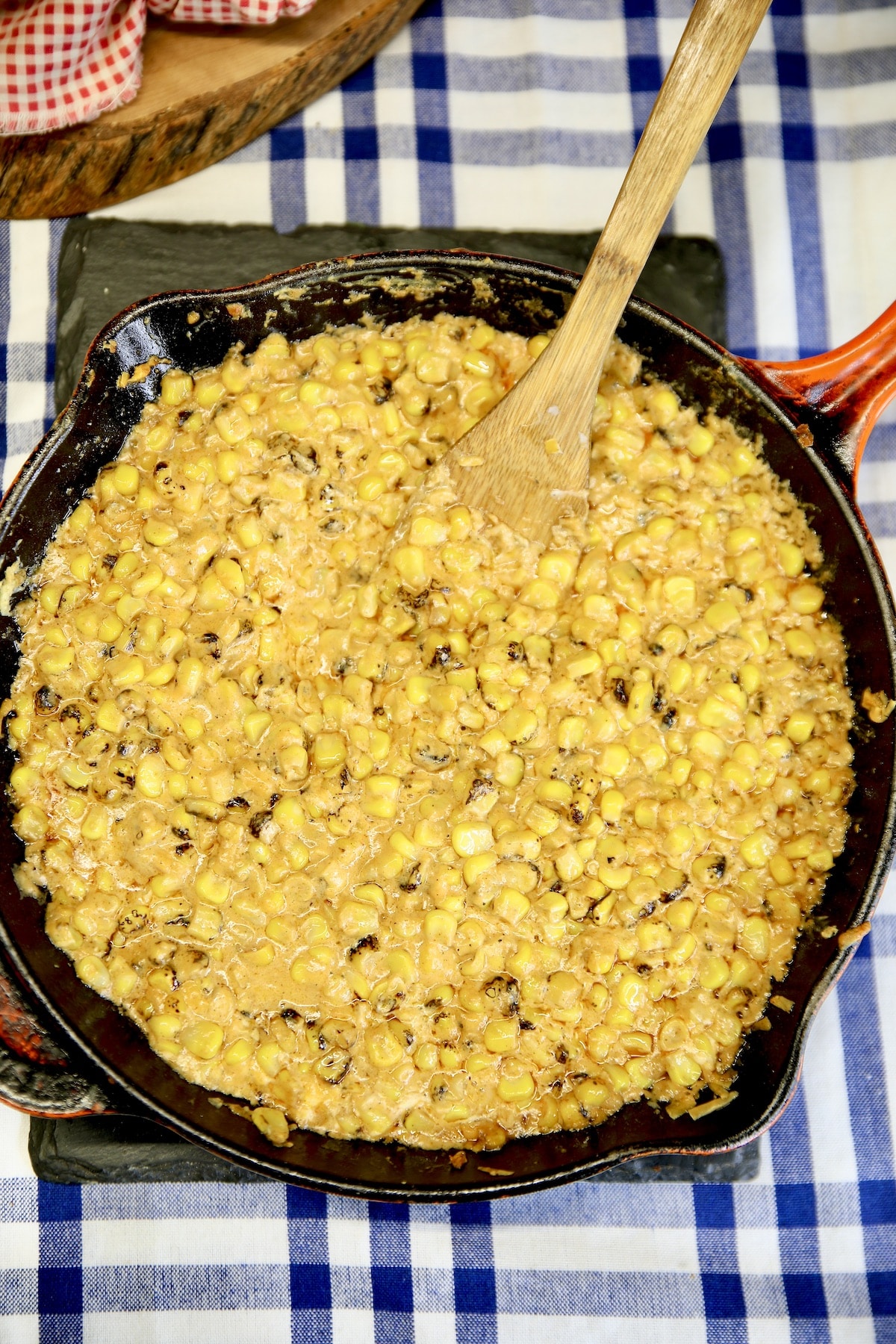 Skillet of creamed corn with a wood spoon.