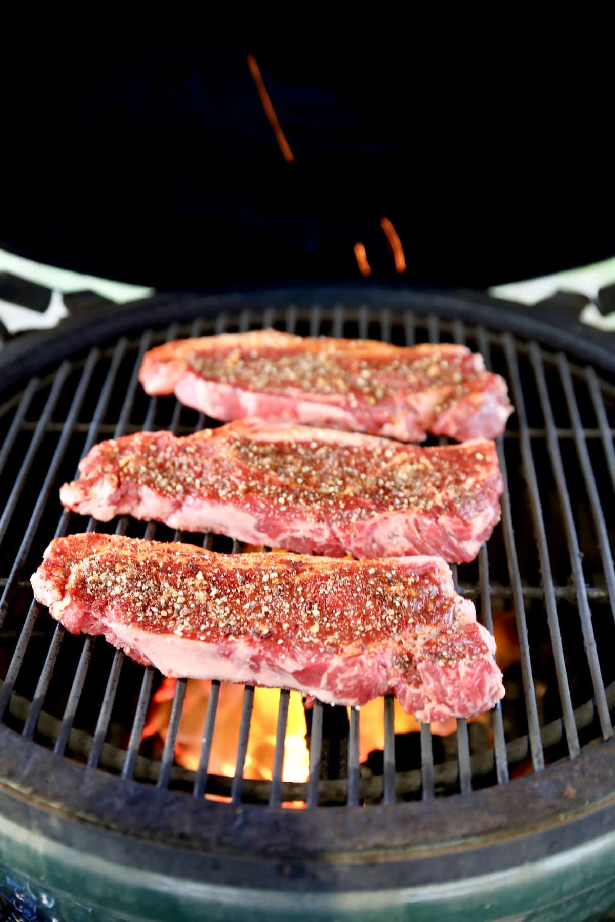3 Strip steaks on a grill.