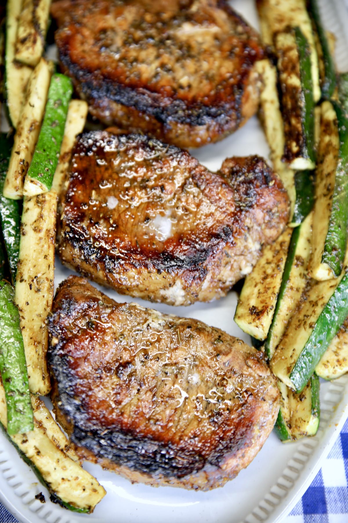 Grilled pork chops on a platter with zucchini.