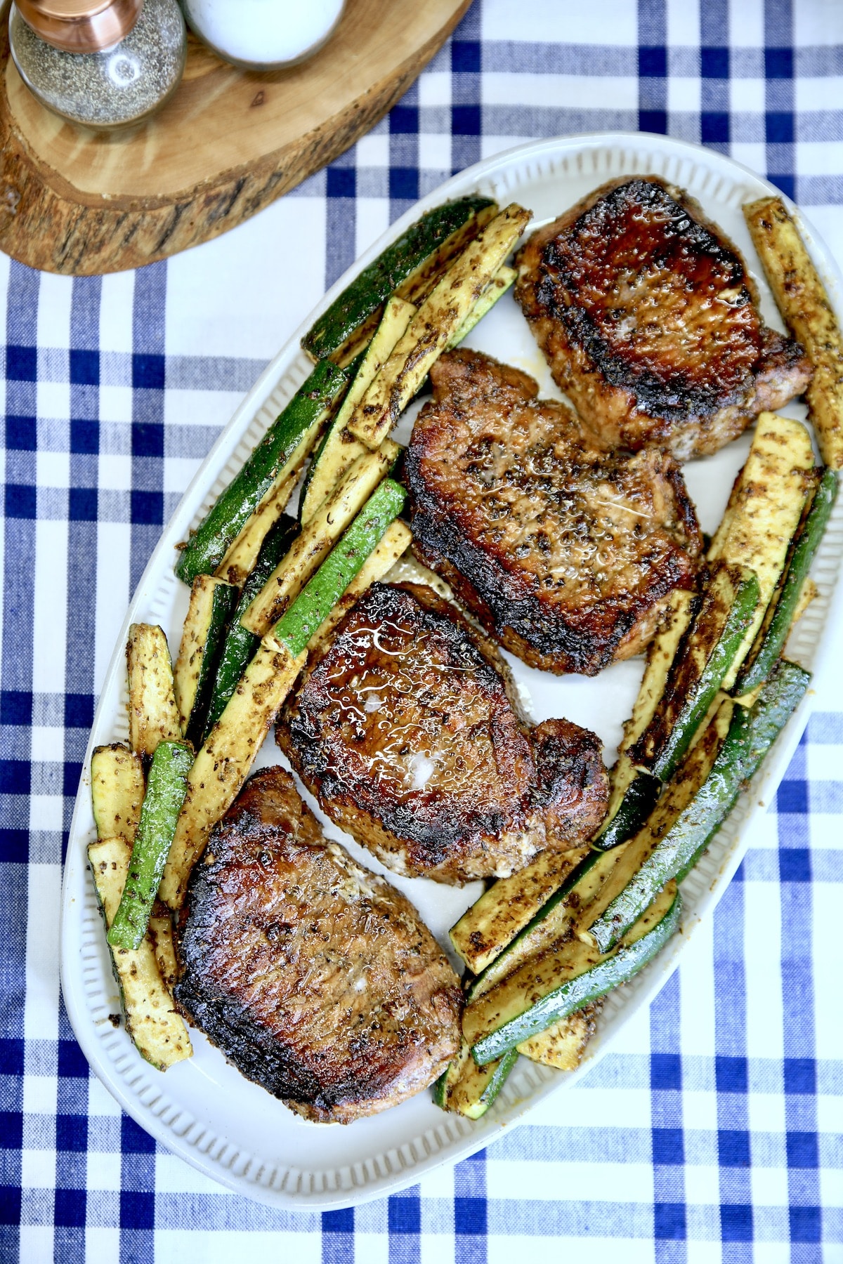 Grilled pork chops with zucchini on a platter.